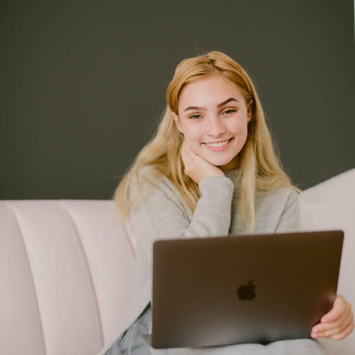 A woman sitting with a laptop and thinking about content creation